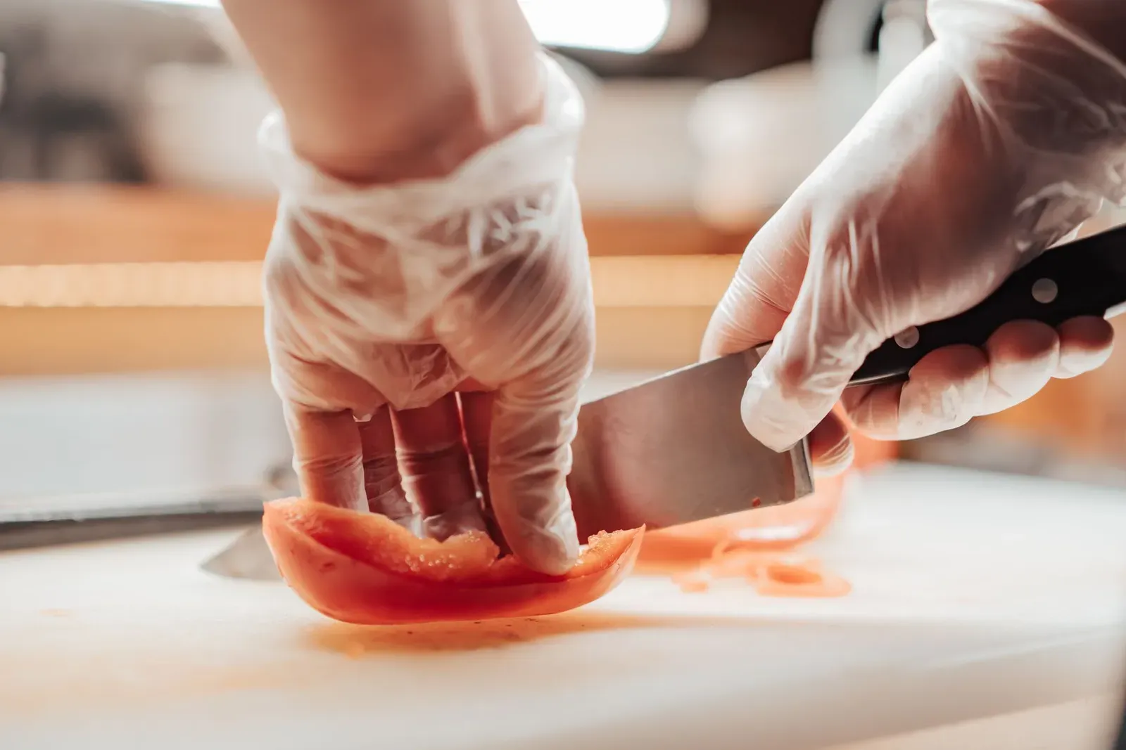 Pracownik gastronomii w rękawiczkach kroi żywność – praca wymagająca orzeczenia sanepidowskiego